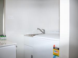 a white kitchen with a sink and a refrigerator at Jacks Lodge Townhouse in Hanmer Springs