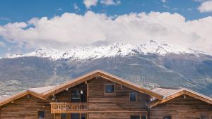 a log cabin with snow covered mountains in the background at SWISSPEAK Resorts Thyon 4 Vallées in Hérémence