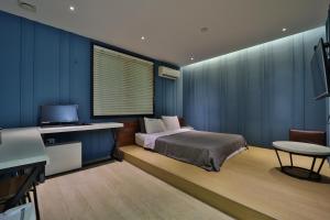 a bedroom with a bed and a desk and a television at Ignis Hotel in Busan