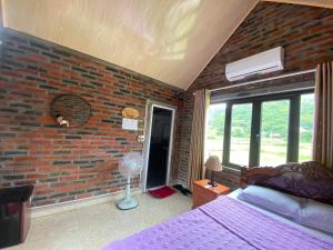Cat Ba Rustic Homestay في كات با: غرفة نوم بحائط من الطوب وسرير ومروحة