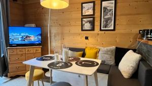 een woonkamer met een tafel en een tv bij Le 41 du Lyret - Appartement type studio pour deux avec vue sur les Aiguilles dans Chamonix Centre in Chamonix-Mont-Blanc +29 foto's