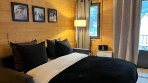 een slaapkamer met een bed met zwart-witte kussens bij Le 41 du Lyret - Appartement type studio pour deux avec vue sur les Aiguilles dans Chamonix Centre in Chamonix-Mont-Blanc