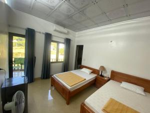 um quarto com 2 camas e uma ventoinha em Cat Ba Rustic Homestay em Ilha de Cát Bà