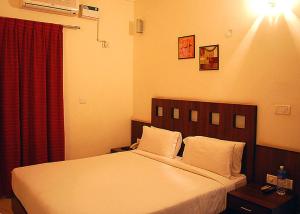 a bedroom with a bed and a red curtain at Silicon Hearth Service Apartments in Bengaluru +15 photos