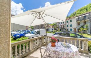 einen Tisch mit einem weißen Regenschirm auf dem Balkon in der Unterkunft 1 Bedroom Pet Friendly Apartment In Loco Di Rovegno in Torriglia