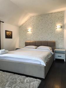 1 dormitorio con 1 cama grande con sábanas blancas en Pensiunea Sub Horiță en Leordina