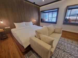 um quarto com uma cama, um sofá e 2 janelas em The Folkster House Chiangkhan em Chiang Khan