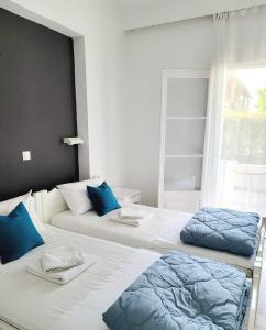 two beds in a room with blue pillows on them at Kalimera Studios and Apartments in Moraitika