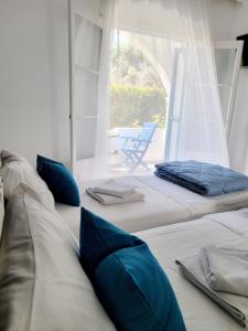Habitación con 3 camas y almohadas azules. en Kalimera Studios and Apartments en Moraitika