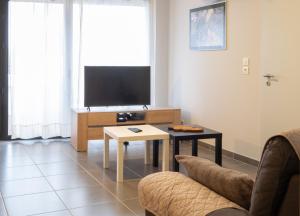 a living room with a tv and a couch and a table at Printemps chaleureux T4 +2 place de parking privée in Annecy