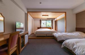 a hotel room with two beds and a television at Hakuba Panorama Hotel in Hakuba
