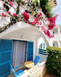a patio with blue doors and flowers on a building at Kalimera Studios and Apartments in Moraitika