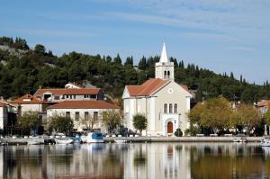 a white church with a steeple next to a body of water at Apartment Ivante in Zaton