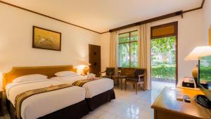 Habitación de hotel con 2 camas y escritorio en Jayakarta Hotel Lombok, en Senggigi 