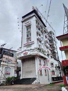 Un edificio alto y blanco con un cartel. en YMCA International Guest House, en Trichūr