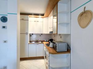 a kitchen with white cabinets and a microwave at Appartamento Gradenigo in Grado