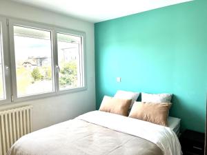 Schlafzimmer mit blauen Wänden und einem Bett mit Kissen in der Unterkunft M19*Marquer* T4 proche frontière in Annemasse