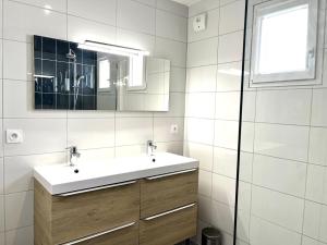 ein weißes Badezimmer mit einem Waschbecken und einem Spiegel in der Unterkunft M19*Marquer* T4 proche frontière in Annemasse