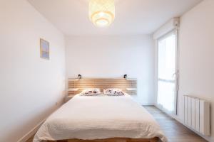 ein weißes Schlafzimmer mit einem großen Bett und einem Fenster in der Unterkunft Superbe T2 gare Annemasse avec Garage et balcon in Ville-la-Grand