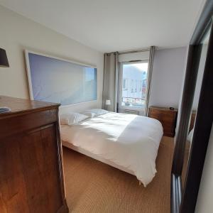 1 dormitorio con cama blanca y ventana en Appartement avec terrasse, en Saint-Denis