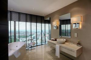 ein Badezimmer mit zwei Waschbecken, einer Badewanne und einem großen Fenster in der Unterkunft Grand Ankara Hotel Convention Center in Ankara