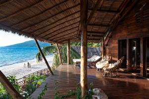 a wooden deck with chairs and a table on the beach at Shambala Madagascar: Beachfront Lodge And Adventures in Ambolobozo