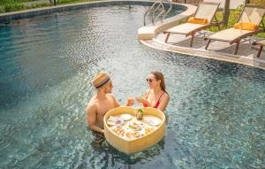 mężczyzna i kobieta siedzący w koszu w basenie w obiekcie Hoi An Babylon Riverside Hotel & Spa w Hoi An