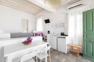 ein weißes Wohnzimmer mit einem weißen Tisch und Stühlen in der Unterkunft Fos Apartments Mykonos in Agios Ioannis Mykonos