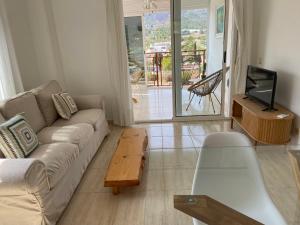 ein Wohnzimmer mit einem Sofa, einem TV und einem Tisch in der Unterkunft Apartamento en Voramar a 2 minutos de la playa in Benicàssim