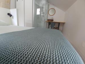ein Schlafzimmer mit einem Bett mit einer grauen Tagesdecke in der Unterkunft Villandry centre Appartement duplex entièrement rénové, au calme in Villandry