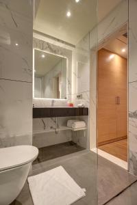 een badkamer met een wastafel, een toilet en een spiegel bij Hotel Mumbai House Ghansoli, Navi Mumbai in Navi Mumbai