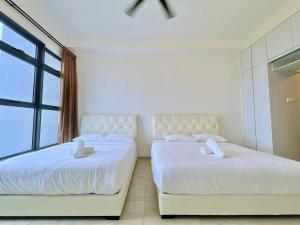 2 białe łóżka w pokoju z oknem w obiekcie Atlantis Residences Melaka w Malakce