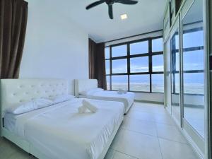 two beds in a bedroom with a view of the ocean at Atlantis Residences Melaka in Melaka