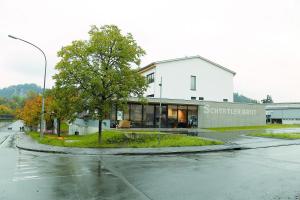 een wit gebouw met een boom in het midden van een straat bij Business Motel Feldkirch in Feldkirch
