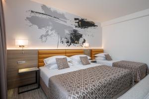 a bedroom with two beds and a painting on the wall at Hotel Ivka in Dubrovnik