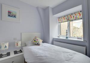 a bedroom with a white bed and a window at Hen Ysgol in Beaumaris