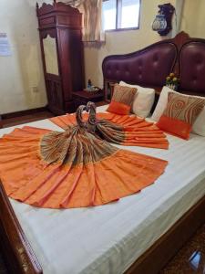 a large bed with an orange blanket on it at Sakura Wood House in Luang Prabang