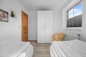 um quarto branco com 2 camas e uma janela em Ferienhaus Westermann em Hooksiel