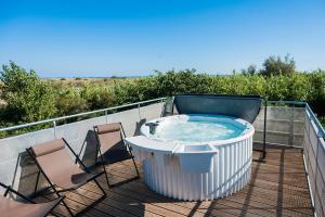 a hot tub on a deck with two chairs at Lodges Méditerranée in Vendres-Plage
