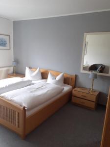 Schlafzimmer mit einem Bett mit weißer Bettwäsche und einem Spiegel in der Unterkunft Pension Hubertus in Winterberg