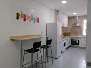 a kitchen with a counter with chairs and a refrigerator at El Hostalito in Ontinyent