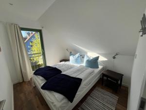 a bedroom with a bed with blue pillows and a window at Meeresrauschen 10 in Groß Kirr
