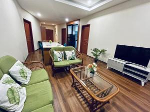 Kuching City Center Riverbank Suites With Marvelous River View في كوتشينغ: غرفة معيشة بها أريكة وكراسي وتلفزيون