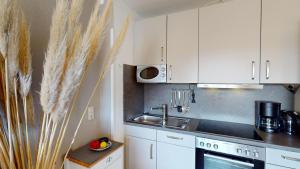 Una cocina con gabinetes blancos y un fregadero. en Das Solaris 9 Luxury Beach Apartment mit Balkon und moderner Ausstattung, en Grömitz