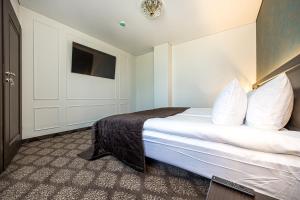 Habitación de hotel con cama con almohadas blancas en Gradiali Wellness and SPA en Palanga