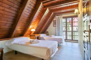 Duas camas num quarto com tectos em madeira em Luderna - Tríplex Nin C2 Arenho em Naut Aran