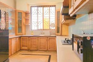 a kitchen with wooden cabinets and a large window at 4Bdr Spacious Hill View Central E 11 TV Netflix in Islamabad