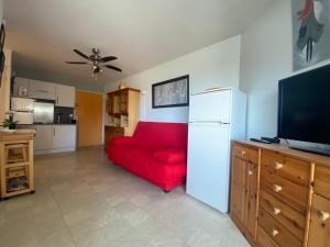 sala de estar con sofá rojo y TV en Sol-y-Days Californie, Appartement confortable 4 personnes à 300m de la plage, en Le Grau-du-Roi