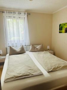 ein großes weißes Bett in einem Schlafzimmer mit Fenster in der Unterkunft La Pura Vida in Bühlertann