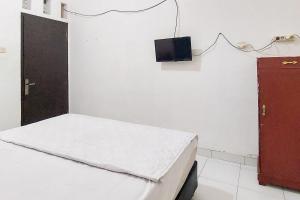 Cette petite chambre comprend un lit et une télévision murale. dans l'établissement Pondok Gede Dkost Syariah Mitra RedDoorz, à Bekasi